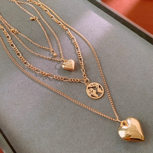 Detail of multi-layered gold necklace with heart charms and a world map pendant