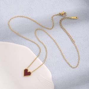 Detailed close-up of a gold chain necklace featuring a red heart pendant with beaded edges