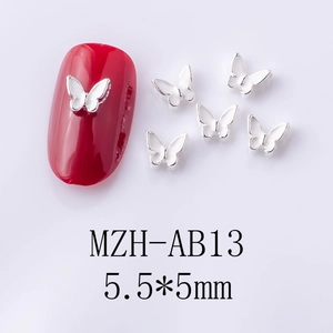 Macro view of 5.5x5mm silver alloy butterfly nail art decor on a red manicure