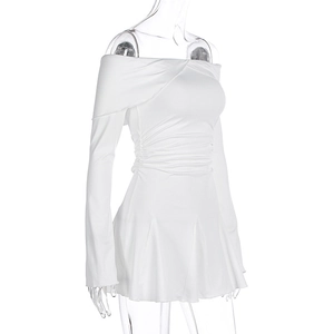 Détail de la robe blanche à manches longues avec taille froncée et jupe plissée