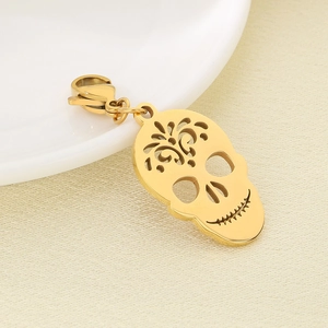 Detail shot of a hollow gold skull pendant with lobster clasp on a white plate