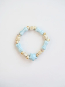 Detail of blue and cream ceramic bracelet featuring star pendant and bone shaped beads