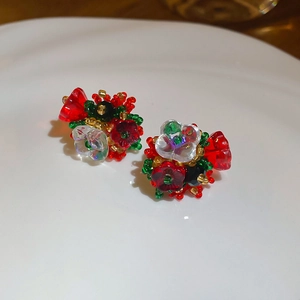 Detailed view of handmade beaded flower cluster earrings on a white ceramic plate