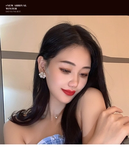 Close-up of sparkling floral stud earrings with clear crystals on female model ear