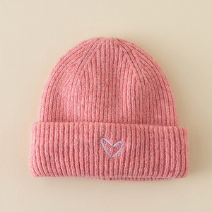 Close-up of pink knit baby hat featuring a purple embroidered heart and ribbed cuff detail