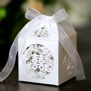 Macro view of white laser-cut wedding favor box with double happiness pattern and silk ribbon