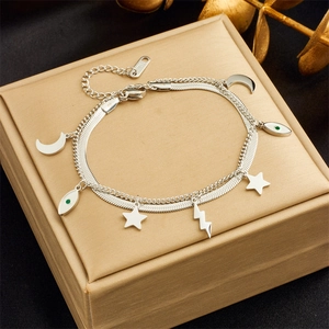 Detail of silver double-layer bracelet with moon, star and eye charms on a jewelry box