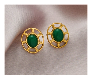 Détail de boucles d'oreilles vintage dorées avec gravures et pierres vertes
