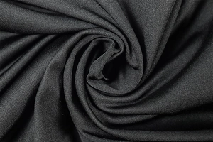 Macro detail of black ruched knit fabric showing texture and flexibility of the dress