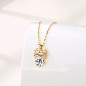 Macro shot of gold bow necklace with clear zircon stones on a white ceramic cup