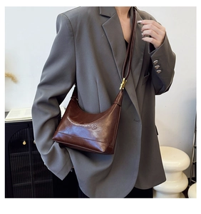 Detailed view of brown leather shoulder bag with adjustable strap and qoodise branding