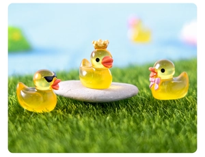 Close-up of mini resin ducks with sunglasses, crown and bow on green grass