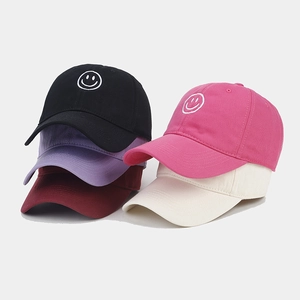 Detailed close-up of colorful cotton baseball caps with embroidered smiley face patterns
