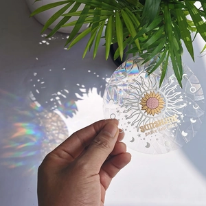 Detail showing holographic suncatcher sticker casting a vibrant rainbow on a white surface