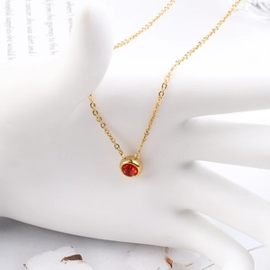 Nahaufnahme der goldenen Edelstahlkette mit rundem rotem Zirkonia-Anhänger auf einer Hand