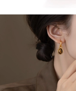 Macro detail of oval tiger eye stone earrings with high-end gold plated silver needle