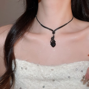 Close-up of elegant black heart pendant necklace with shimmering beaded chain on a model