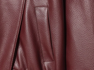 Detailed macro view of the side pocket on a burgundy faux leather jacket with lychee texture