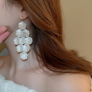 Detail showing long white shell flower tassel earrings with rhinestone on female model
