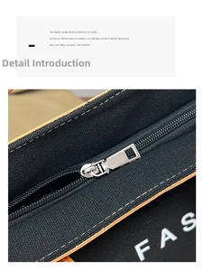 Close-up of black canvas bag with silver metal zipper, brown trim and white stitching