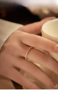 Detailed view of a gold eternity band with micro-pave diamonds worn on finger