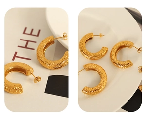 Detail view of gold C-shaped earrings featuring a unique hammered texture and metallic finish