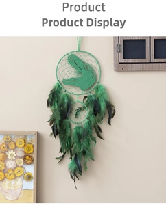 Detail of green dinosaur dream catcher with natural feathers and beads on a beige wall