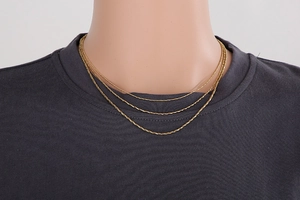Detailed view of triple-layered golden snake chain necklaces on a mannequin bust