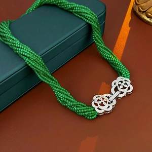 Detail of multi-strand emerald green bead necklace with silver zircon flower clasp