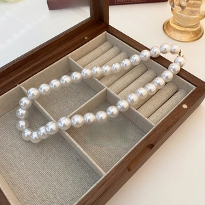 Detailed view of elegant white pearl necklace inside a wooden glass-top jewelry box