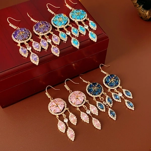 Close-up of vintage gold rhombus tassel earrings with colorful zircon stones on wood