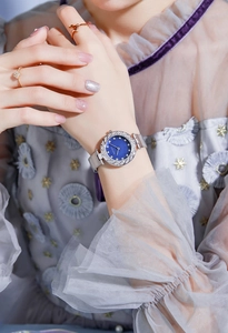 Close-up of elegant silver mesh watch with blue dial and diamond markers on a female wrist