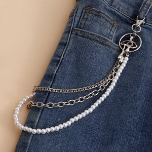 Detail of layered silver metal pant chain with pearls and eye charm on blue denim jeans