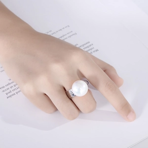 Close-up of a large white pearl ring with a silver hammer-textured band on a hand