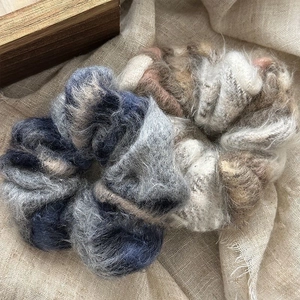 Chouchous en peluche douce bleu-gris et beige sur fond en lin naturel élégant