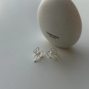 Detailed view of silver bow-shaped earrings with central white pearl and sleek hollow design