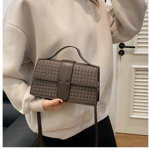 Detailed view of dark brown woven texture and leather flap on the small square bag