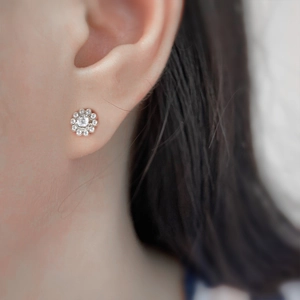 Close-up of a silver flower stud earring with a central zircon and sparkling petals