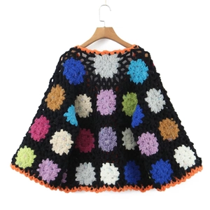Handmade bohemian crochet poncho sweater with colorful floral patterns on black knit