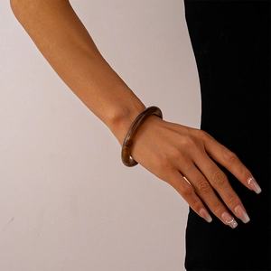 Detailed view of translucent amber acrylic cuff bracelet styled on model wrist