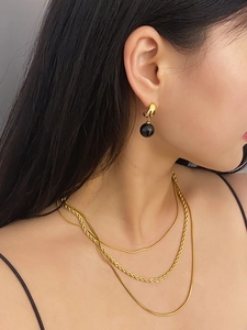 Close-up of gold layered twisted and snake chain necklace on model neck
