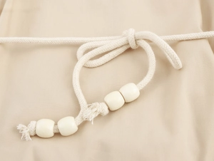 Vue détaillée du cordon en coton beige avec des perles crème sur une robe d'été bohème