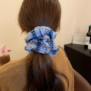 Chouchou en tweed à carreaux bleus porté par un modèle, montrant la texture et les plis