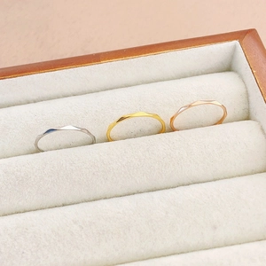 Close-up of three 1mm minimalist geometric rings in silver, gold, and rose gold finish