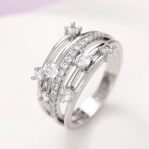 Detalle macro de anillo plateado multicapa cruzado con circonitas brillantes engastadas
