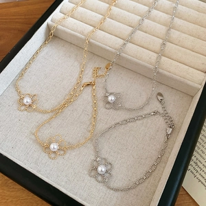 Detail of clover necklaces and bracelets with pearls in gold and silver finish