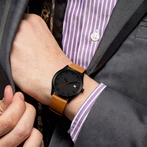 Gros plan d'une montre quartz avec bracelet en cuir marron et cadran noir au poignet