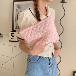 Detailed view of pink quilted cosmetic bag with cute rabbit prints held by a person