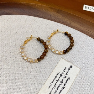 Vintage runde Goldohrringe mit Tigerauge-Perlen und Kristallen auf Holzdisplay