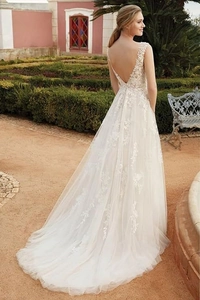 Exquisite back view of a white lace wedding gown with deep V-back and long mesh train